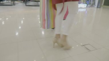 Topuklar ellerinde alışveriş çantaları taşırken bir moda şekilde alışveriş merkezinde yürüyen kadın bacak yakın çekim