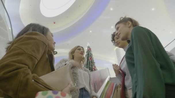 Middelbare Schoolmeisjes in het winkelcentrum genieten van Kerst vakantie roddelen en met behulp van de roltrappen te bereiken van voedsel zone na een winkelsessie — Stockvideo