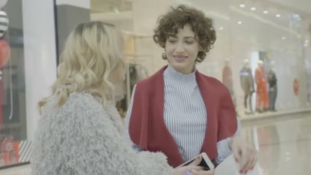 ビジネス マネージャー女性のベンチに座って、予算をショッピング モールのロビーで彼女の 10 代の友人と議論 — ストック動画