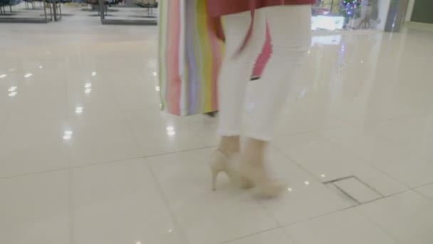 Close up of female legs in heels marching in a fashion way at the mall while carrying shopping bags in their hands — Stock Video