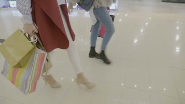 Крупный план молодых модных наркоманов девушки на каблуках маршируют в торговом центре, чтобы сделать покупки в выходные дни — стоковое видео
