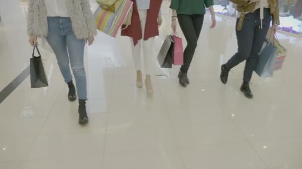 Laag schot van groep van vrouwelijke benen lopen in de lobby van de mall bij boodschappentassen in hun handen — Stockvideo