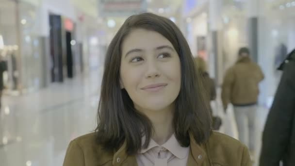 Портрет счастливой ангельской предпринимательницы, смотрящей в сторону и улыбающейся в камеру перед тем, как начать шоппинг в торговом центре — стоковое видео