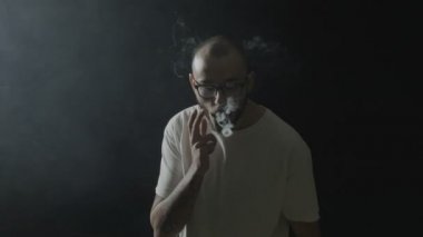 Vaping hileler gösterilen ve küçük daire ile siyah bir zemin üzerine elektronik sigara dumanının yapım genç vaper adam