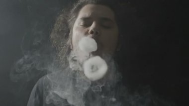 Portresi bir yetişkin bir vaper uzun saçlı elektronik sigara teneffüs edilmesi sonra etkileyici vaping Buhar daire hileci performans