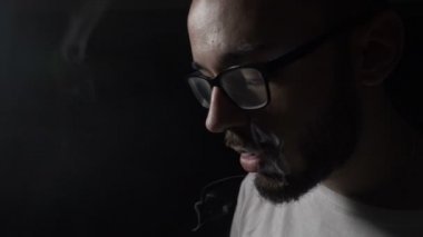 Buhar onun dudağında parçasıyla birlikte kullanılmalıdır ve burnunda teneffüs edilmesi o zaman duman halkaları ağır çekimde yapma gözlük vaping elektronik sigara ile genç adam sigara bağımlısı