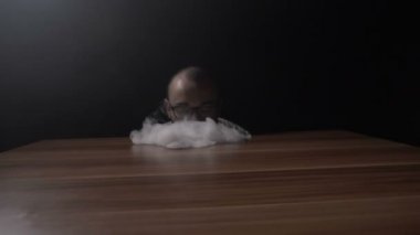 Genç yenilikçi genç çocuk bir buhar dalga tablo ve daha sonra elini ağır çekimde kullanarak bir kasırga yaparken Vaping hileci performans
