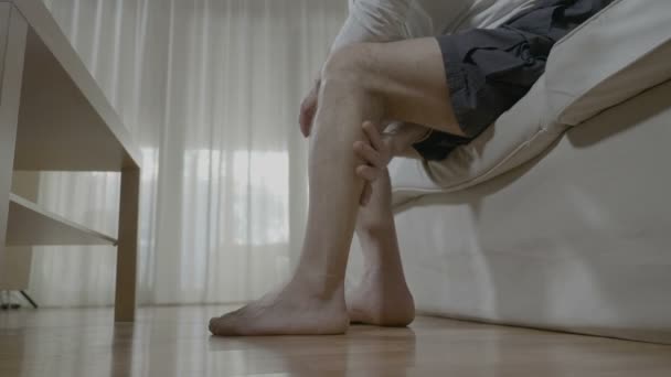 年配の男性が自分で彼の疲れた足でのマッサージ療法をやって痛みや家庭でのストレスを和らげる — ストック動画