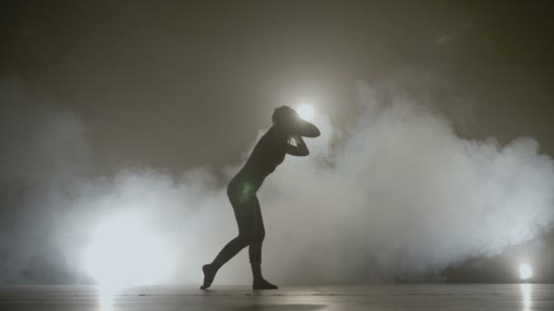 Jovem bela mulher atraente realizando uma dança moderna simples em um palco de fundo de fumaça — Vídeo de Stock