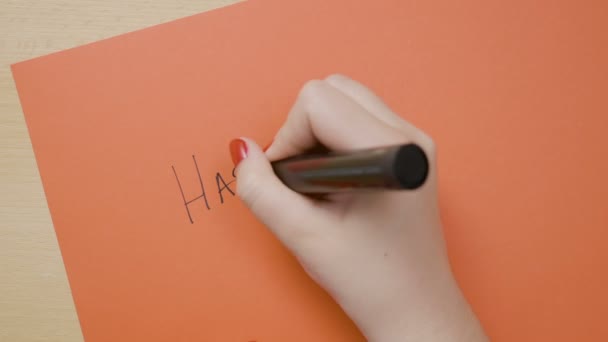 Jovens mãos femininas escrevendo feliz ano novo em papel vermelho com marcador preto — Vídeo de Stock