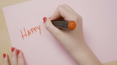 Eller kadın mutlu Sevgililer günü büyük harflerle pembe kağıt üzerinde kırmızı bir marker ile yazma