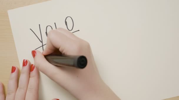 Підліткові жіночі руки з червоним лаком для нігтів написання йоло ви живете тільки один раз мотиваційна цитата на білому папері з чорним маркером — стокове відео