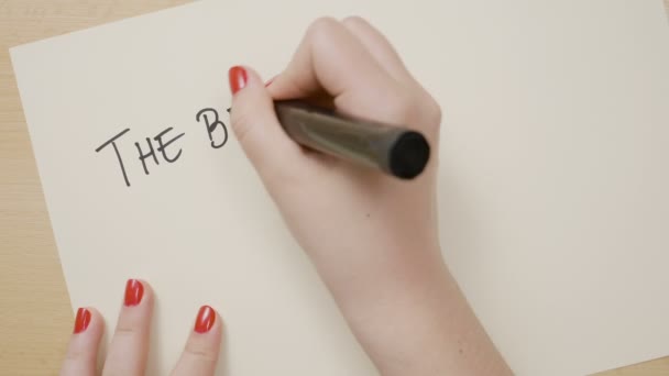 Young female hands writing the best way out is always through exclamation point motivational quote on white paper with a black marker — Stock Video