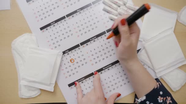Женские руки кружат даты в календаре и задаются вопросом, почему у нее задержка менструации. — стоковое видео
