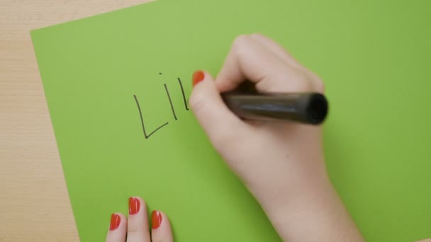Female hands writing like and underlining it on a green paper using a black marker — Stock Video