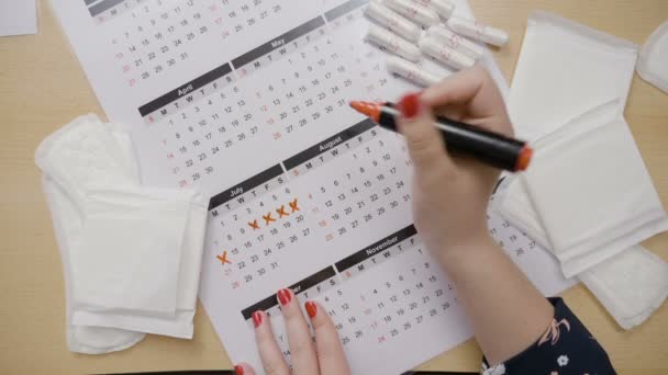 Manos de niña calculando su ovulación y marcando las fechas en un calendario con un marcador naranja mientras pregunta por qué se perdió su período — Vídeo de stock