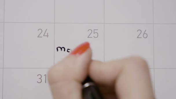 女孩的手与红色指甲的顶部视图写圣诞快乐在12月25日在日历中使用黑色钢笔 — 图库视频影像