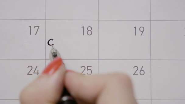 Las manos de la mujer con manicura roja que marca el día en el calendario y la escritura de las niñas de noche en él con pluma negro — Vídeo de stock