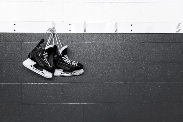Hockey skates hanging in locker room in black and white background with copy space