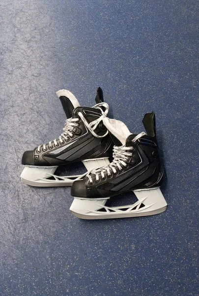 Hockey skates over floor in locker room with blue background and copy space. Vertical