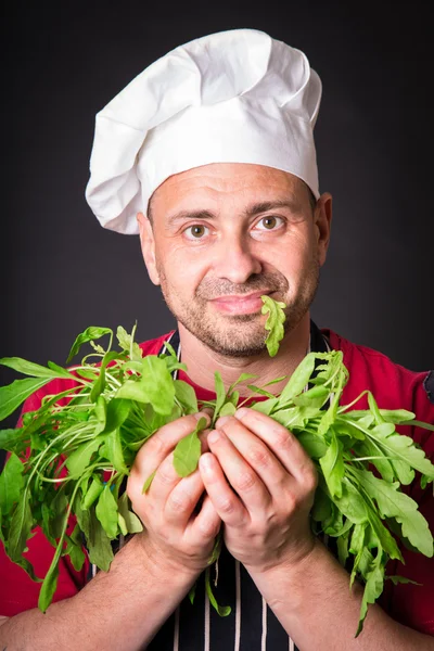 Closeup of happy chef holding arugula beam