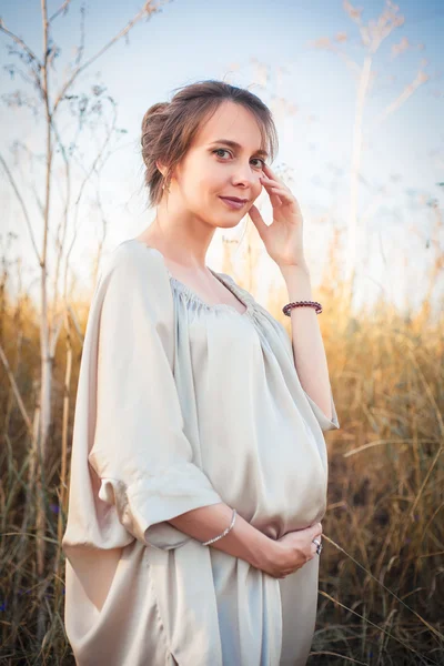 Retrato de uma mulher grávida sob a luz do pôr do sol — Fotografia de Stock