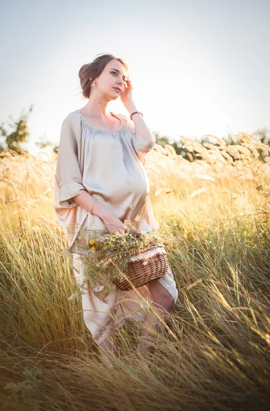 Ung vacker gravid kvinna promenader i ett fält — Stockfoto