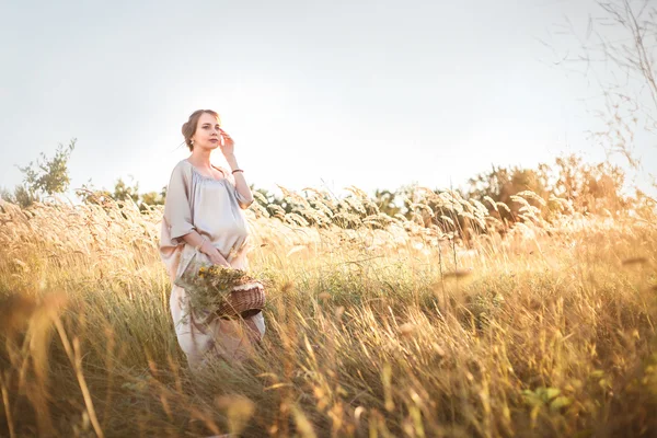 Giovane bella donna incinta che cammina in un campo — Foto Stock