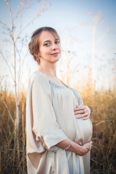 Portret van een zwangere vrouw in de zonsondergang licht — Stockfoto