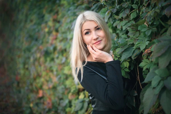 Atraktivní mladá žena na pozadí břečťan listy — Stock fotografie
