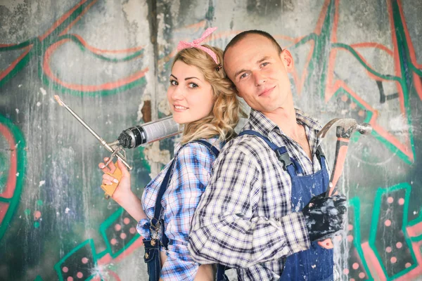 Young couple in overalls with tools. Concept of construction and home repair.