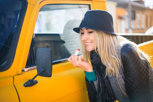 Tatlı genç kadın kırmızı ruj araba aynaya bakarak geçerlidir