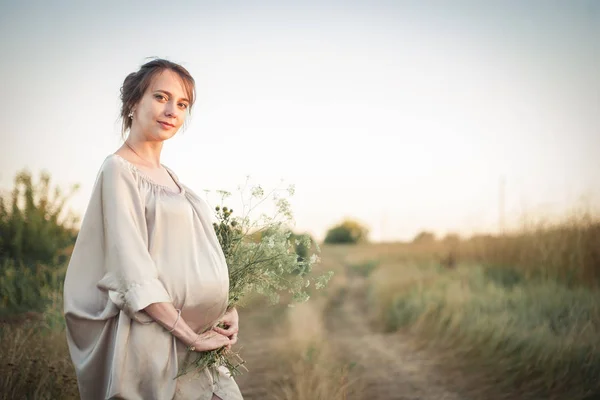 Retrato de uma mulher grávida sob a luz do pôr do sol — Fotografia de Stock