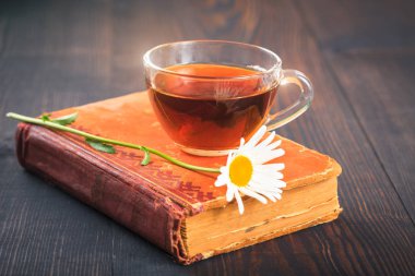 Fincan çay, papatya ve masanın üzerine bir kitap