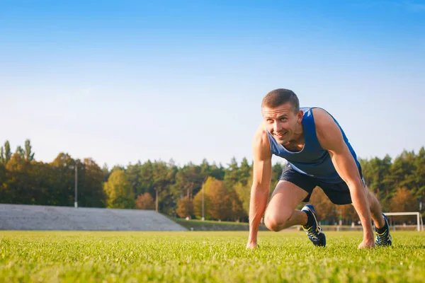 Man in low start position on old stadium.