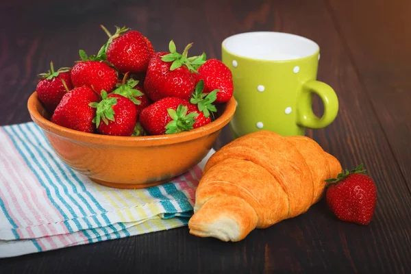 Deska s jahodovou, croissant a hrnek mléka na dřevěný stůl. — Stock fotografie