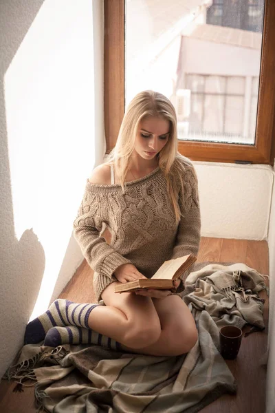 Mooie jongedame in een trui die lezen van een boek. — Stockfoto