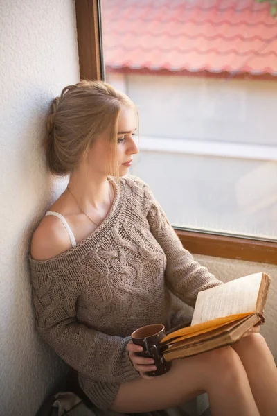 Joven hermosa mujer leyendo por la ventana . —  Fotos de Stock