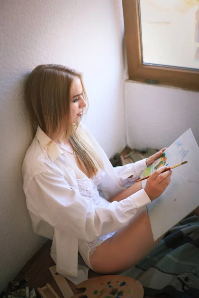 Beautiful woman in a shirt and underwear draws near the window. — Stock Photo, Image