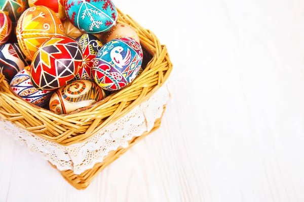 Uova di Pasqua in un cesto su tavolo bianco . — Foto Stock