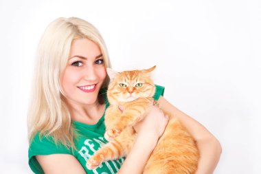 Genç kadın elinde beyaz zemin üzerine kırmızı kedi tutar.