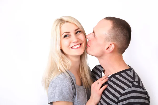 Осторожный мужчина целует свою улыбающуюся девушку на белом фоне . — стоковое фото
