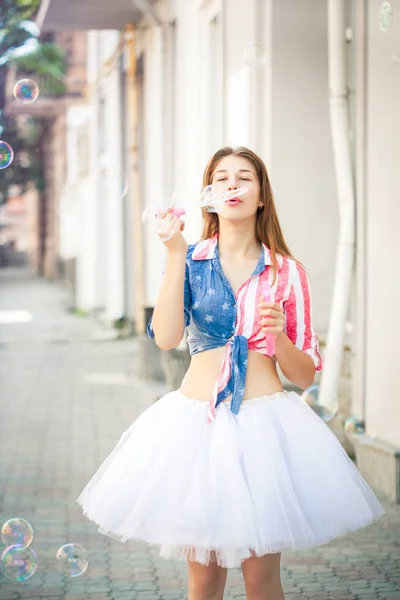 Ein Teenager-Mädchen bläst Blasen auf der Straße. — Stockfoto