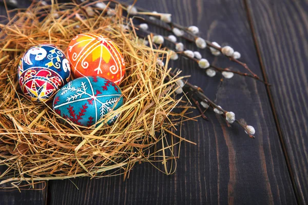 Húsvéti tojást egy kosárban, a fűzfa ágakat egy fából készült asztal. — Stock Fotó