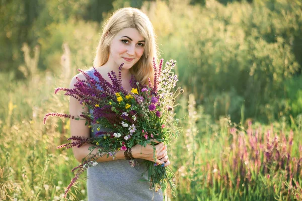 Ritratto di una giovane bella donna nella natura con un mazzo di fiori . — Foto Stock