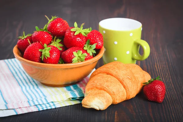 Deska s jahodovou, croissant a hrnek mléka na dřevěný stůl. — Stock fotografie