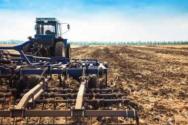 Bir pulluk ile eski mavi traktör.