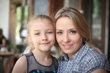 Gülümseyen genç anne ve kızı yakın çekim açık havada portre.