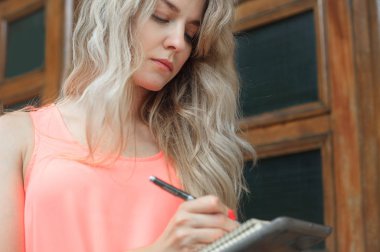 güzel genç kadın bir not defterinde yazıyor.