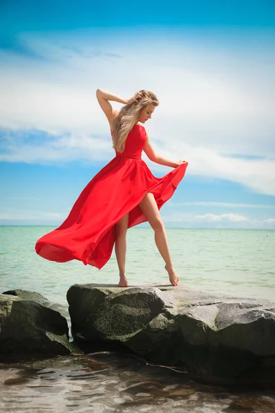 Krásná žena v zářivě červené šaty u moře. — Stock fotografie